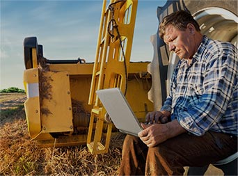 farmer sitting on a large tire checking energy use